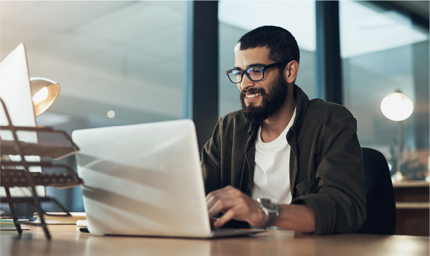 Man writing at desk on laptop