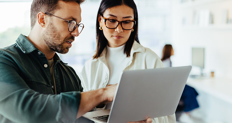 Man showing something to colleague on laptop